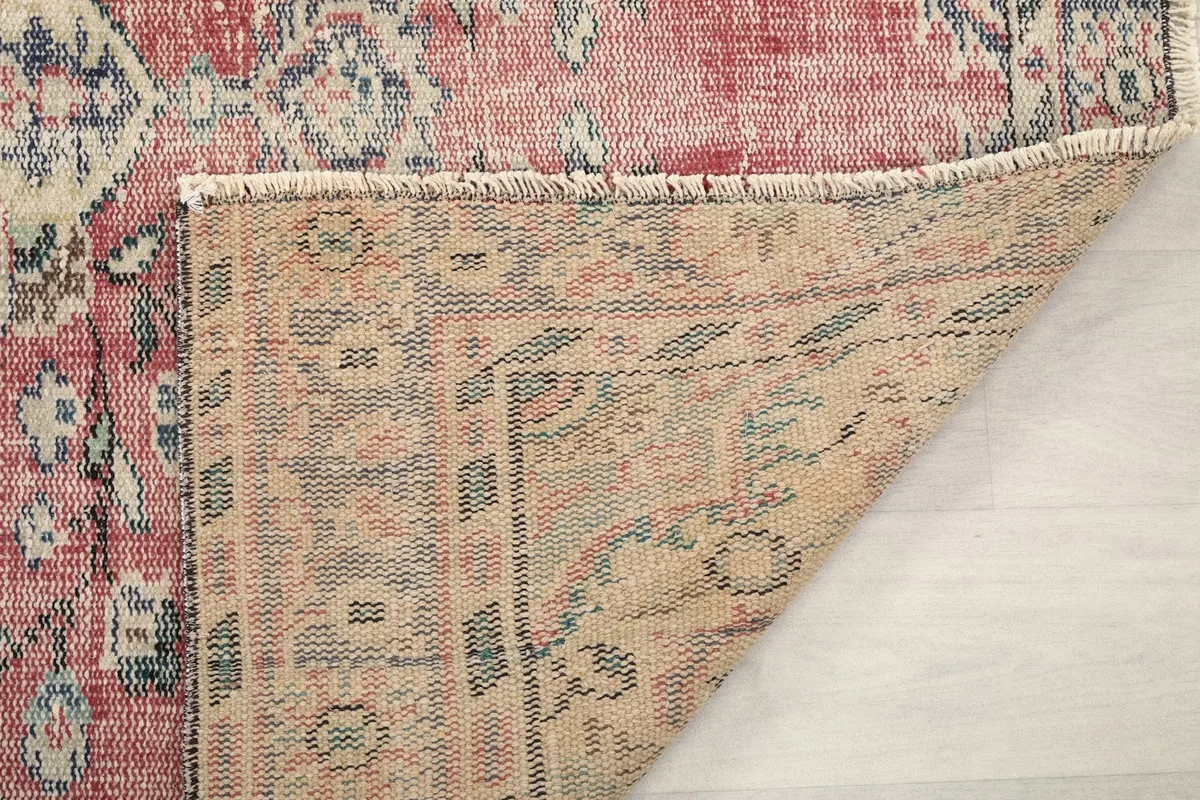 Corner of the rug folded back to reveal the construction and foundation