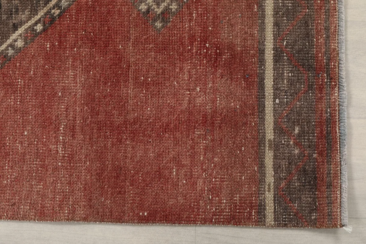 Detail view of the rust field and the subtle border area of the vintage hand-knotted wool rug.