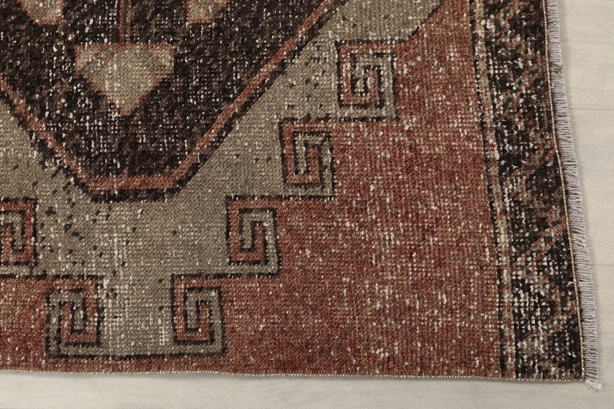Detailed view of the rug's edge and a beige geometric motif with a rust field, showing the low pile.