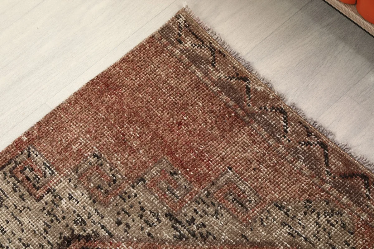 Corner detail of the rug, showing the worn fringe and the transition from the field to the edge.