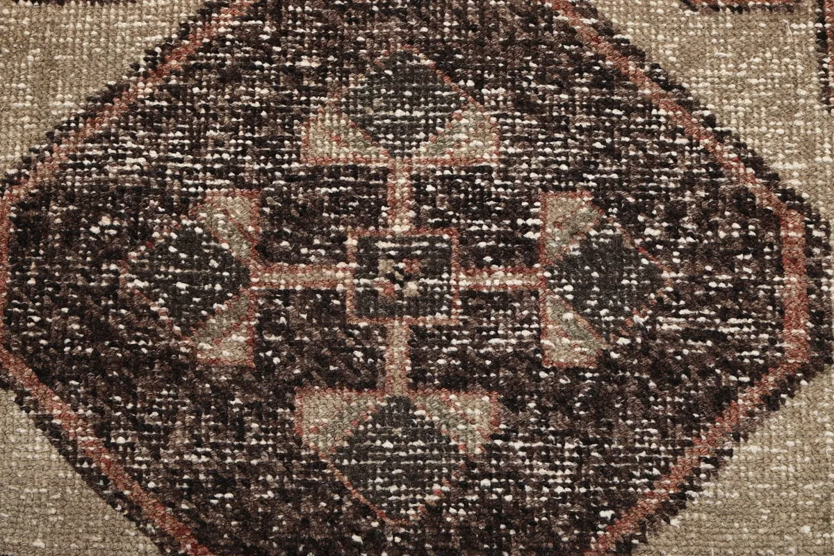 Extreme close-up of the hand-knotted wool pile, revealing the texture and subtle color variations within the charcoal motif.
