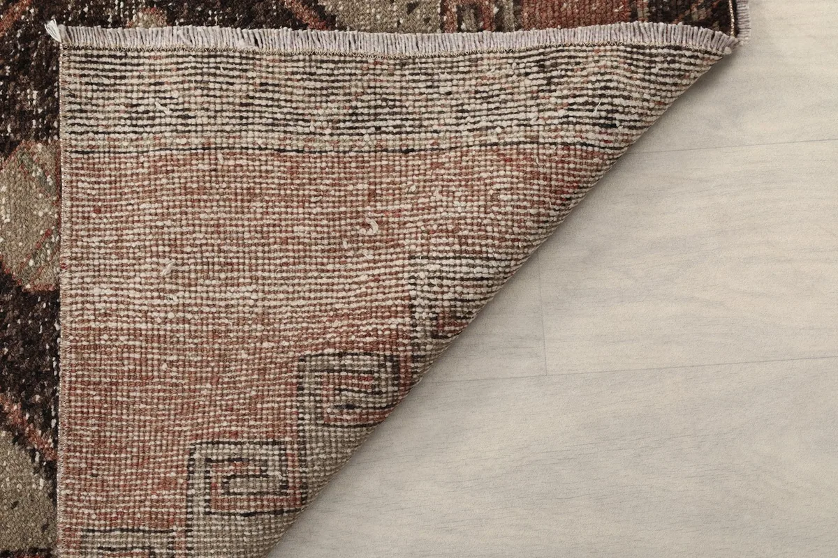 Underside of the rug visible as a corner is folded, showing the hand-knotted cotton foundation.