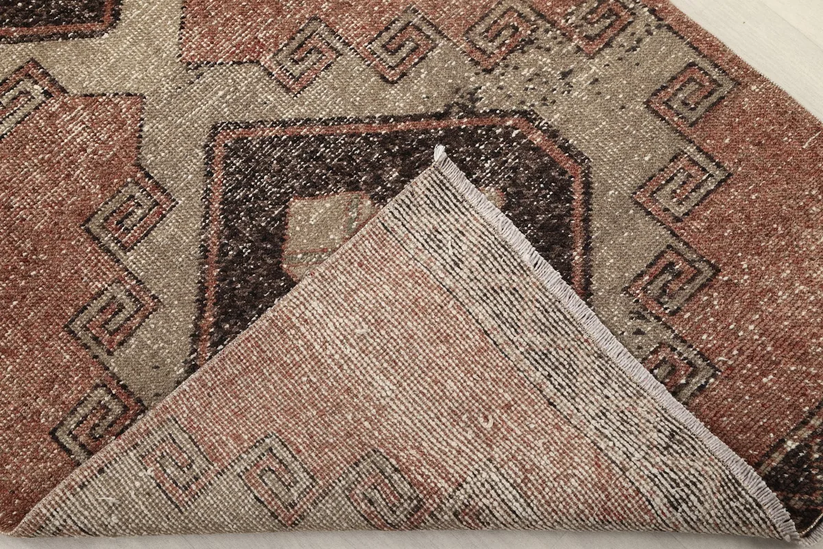 Corner of the rug folded back, revealing the wool pile on the top surface and the cotton foundation beneath.