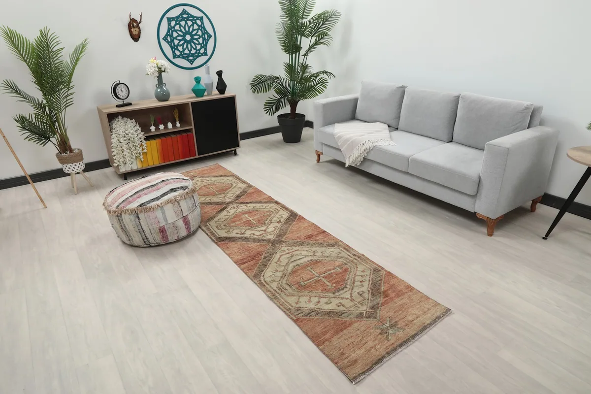 Angled view of the rust and ivory geometric runner rug in a room setting, showing its length.