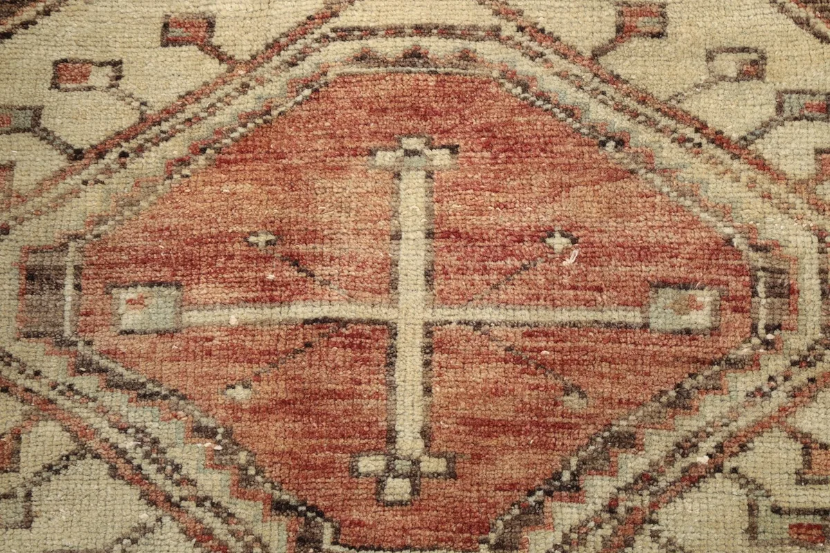Detailed view of the intricate motifs within an ivory and rust geometric diamond pattern.