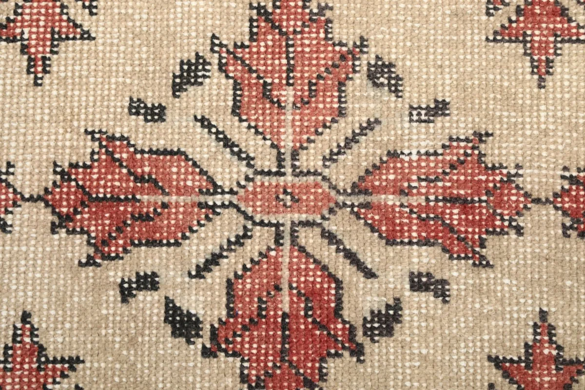 Close-up of a single rose and black geometric motif with visible wool pile texture