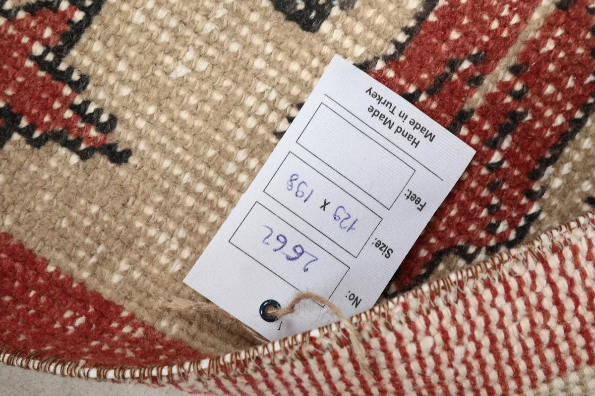 Close-up of the rug's back side with a size tag displaying 129 x 198 cm
