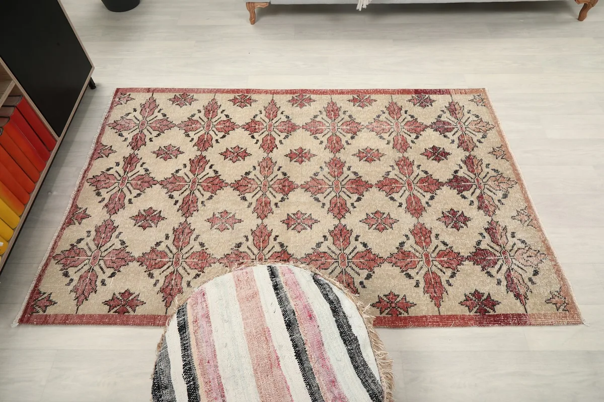 Full overhead view of the 4'3" x 6'6" beige and rose vintage rug in a room