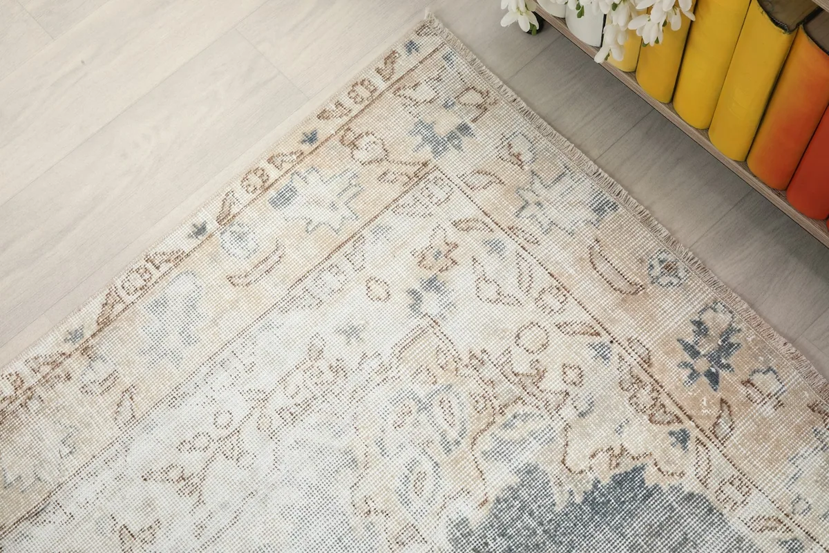 Angled detail of a corner of the rug, showing the blend of gray, beige, and blue in the border design