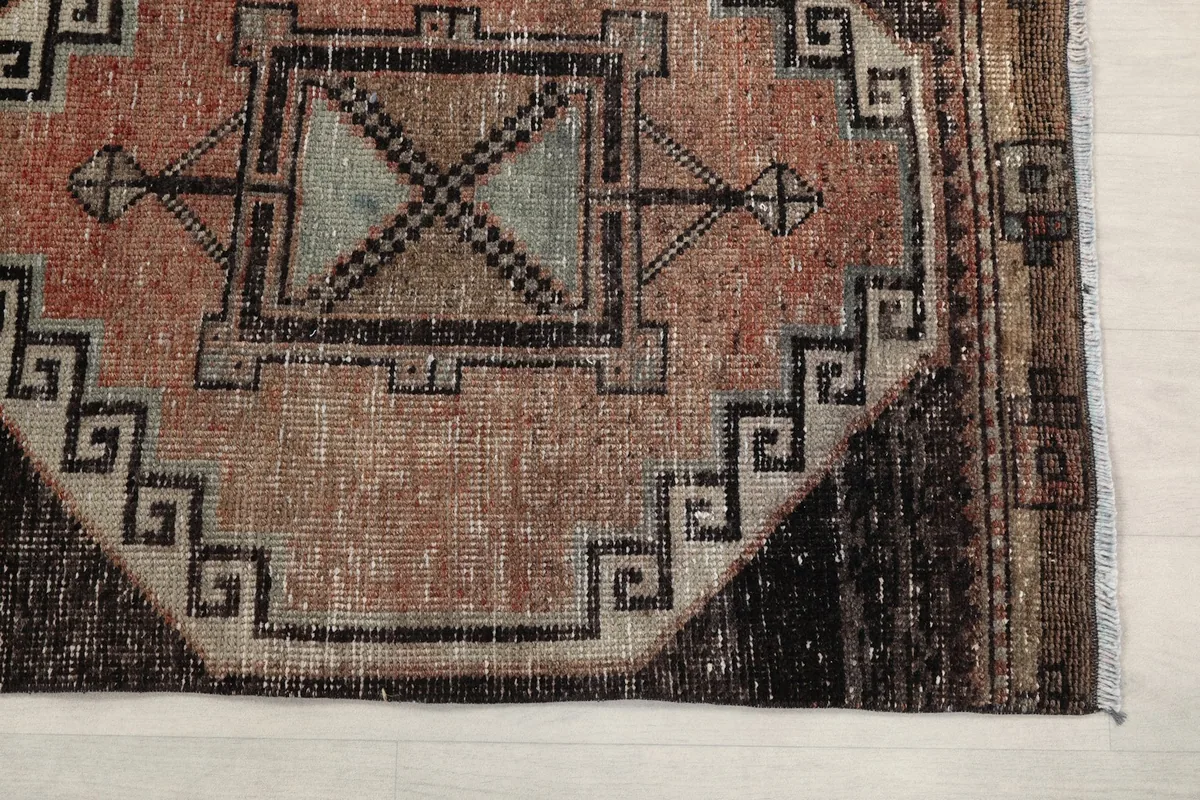 Detailed view of the rose and black geometric pattern with visible wear and low pile