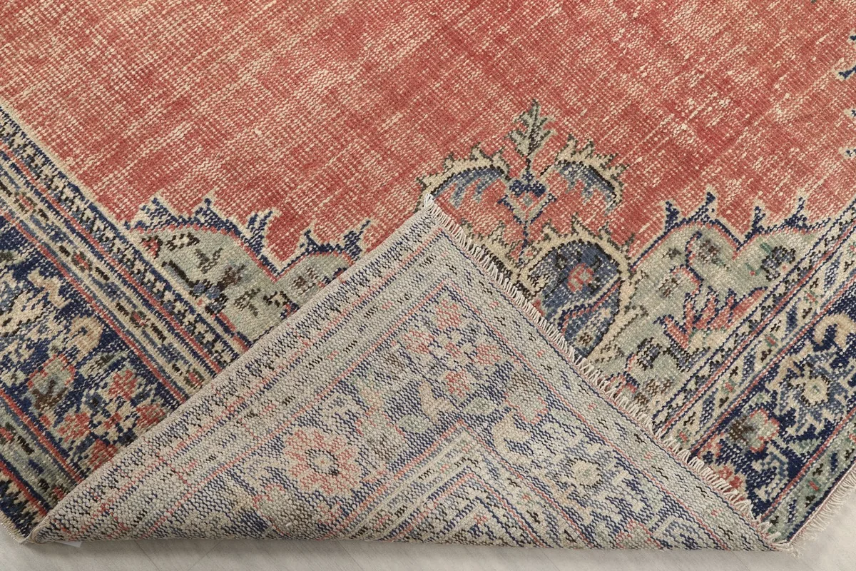 Folded corner of the rug revealing the cotton foundation and the reverse side of the hand-knotted design