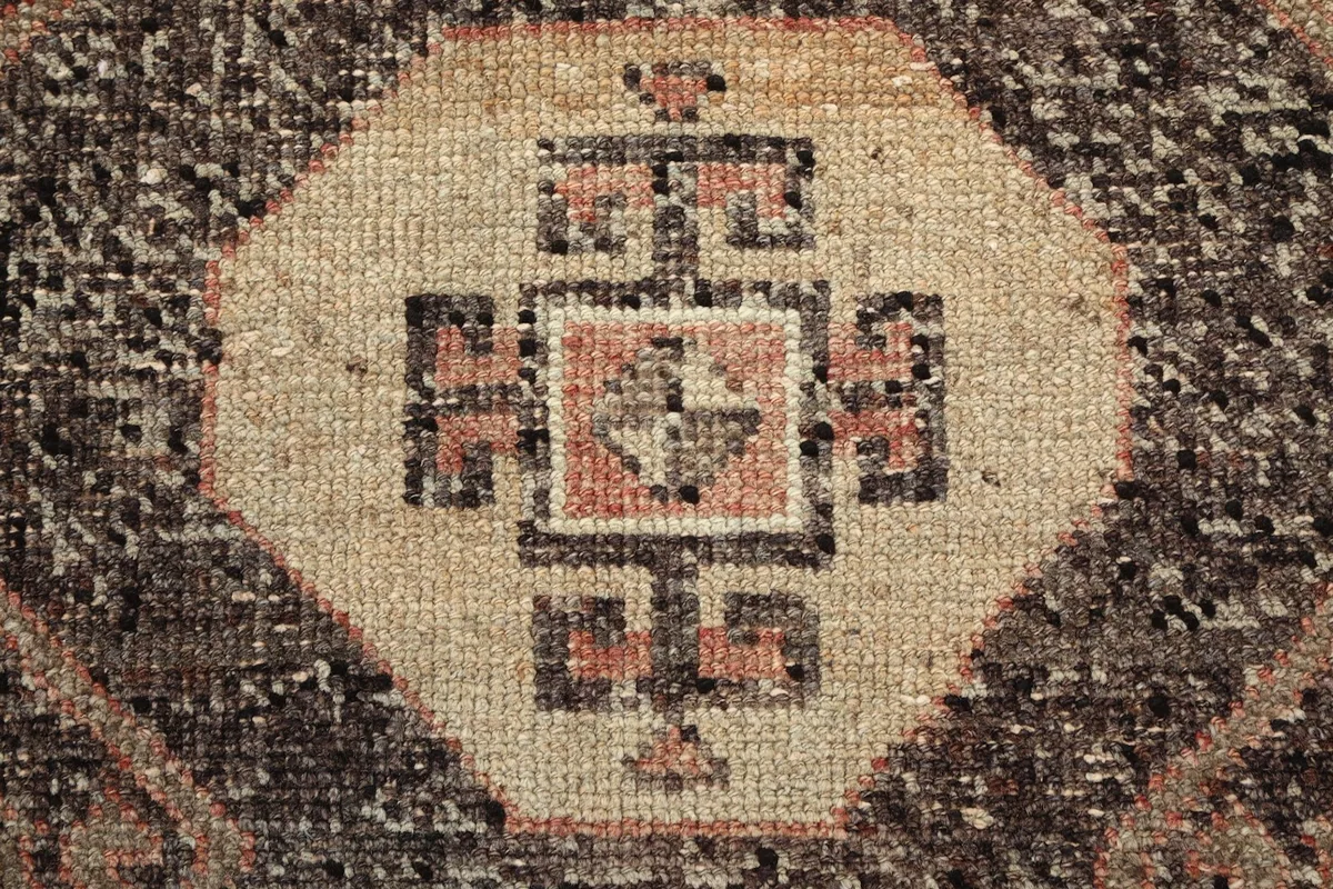 Macro detail of the hand-knotted wool pile within a beige and rust geometric design.