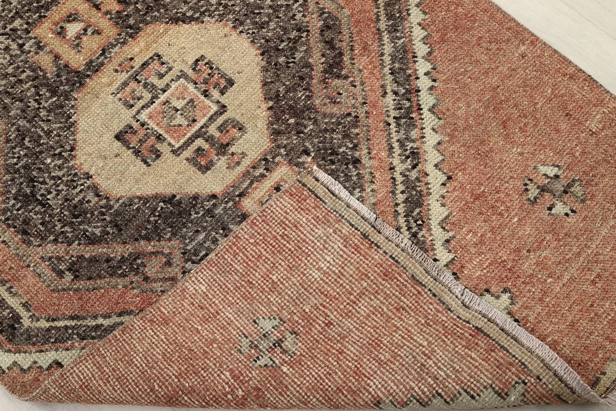 View of the rug's reverse side and a corner of the pile, showing the cotton foundation.