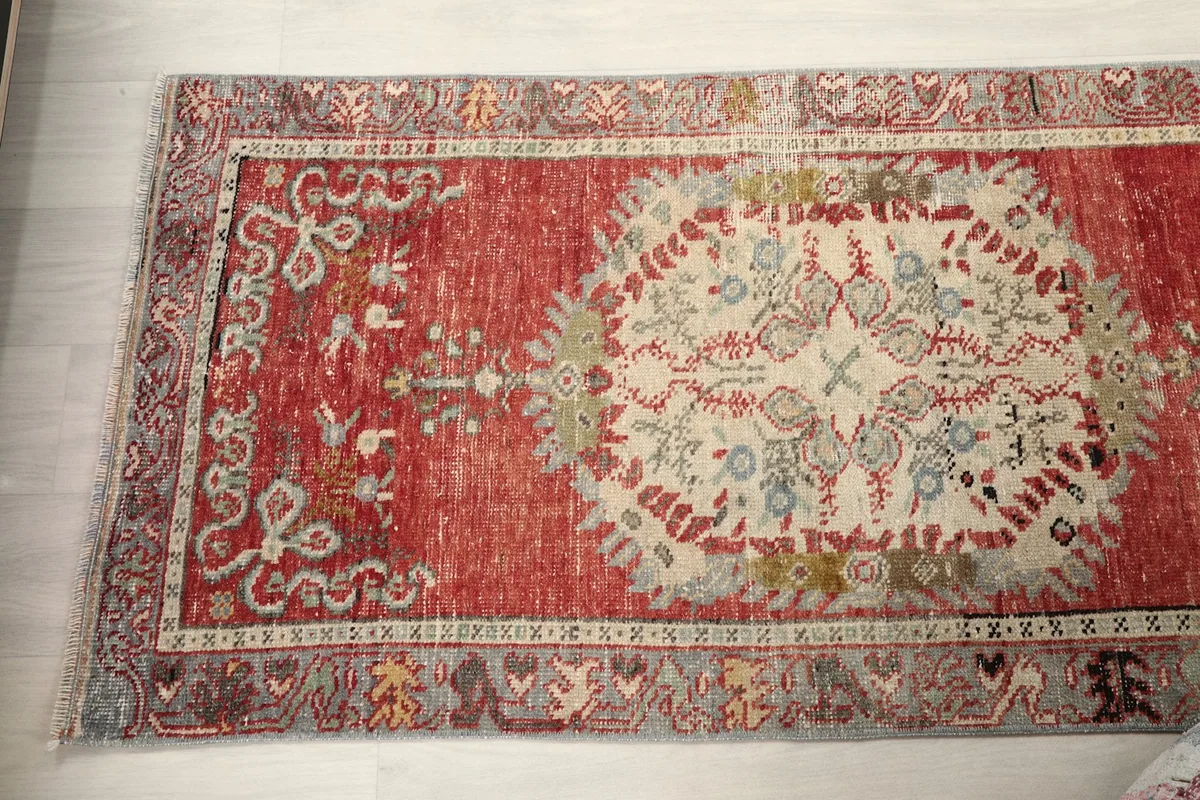 Angled view showing a full medallion and part of the red field, emphasizing the rug's vintage character