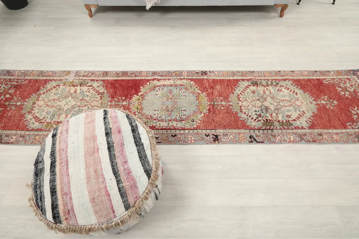 Wide view of the red runner rug in a room, showing its length relative to a couch and ottoman