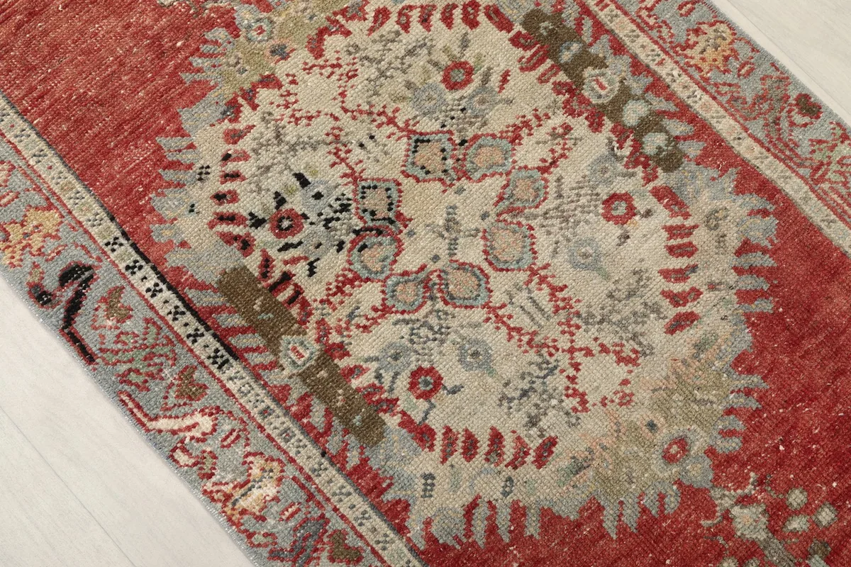 Close-up of a faded central medallion in ivory, beige, and blue on the red field of the runner