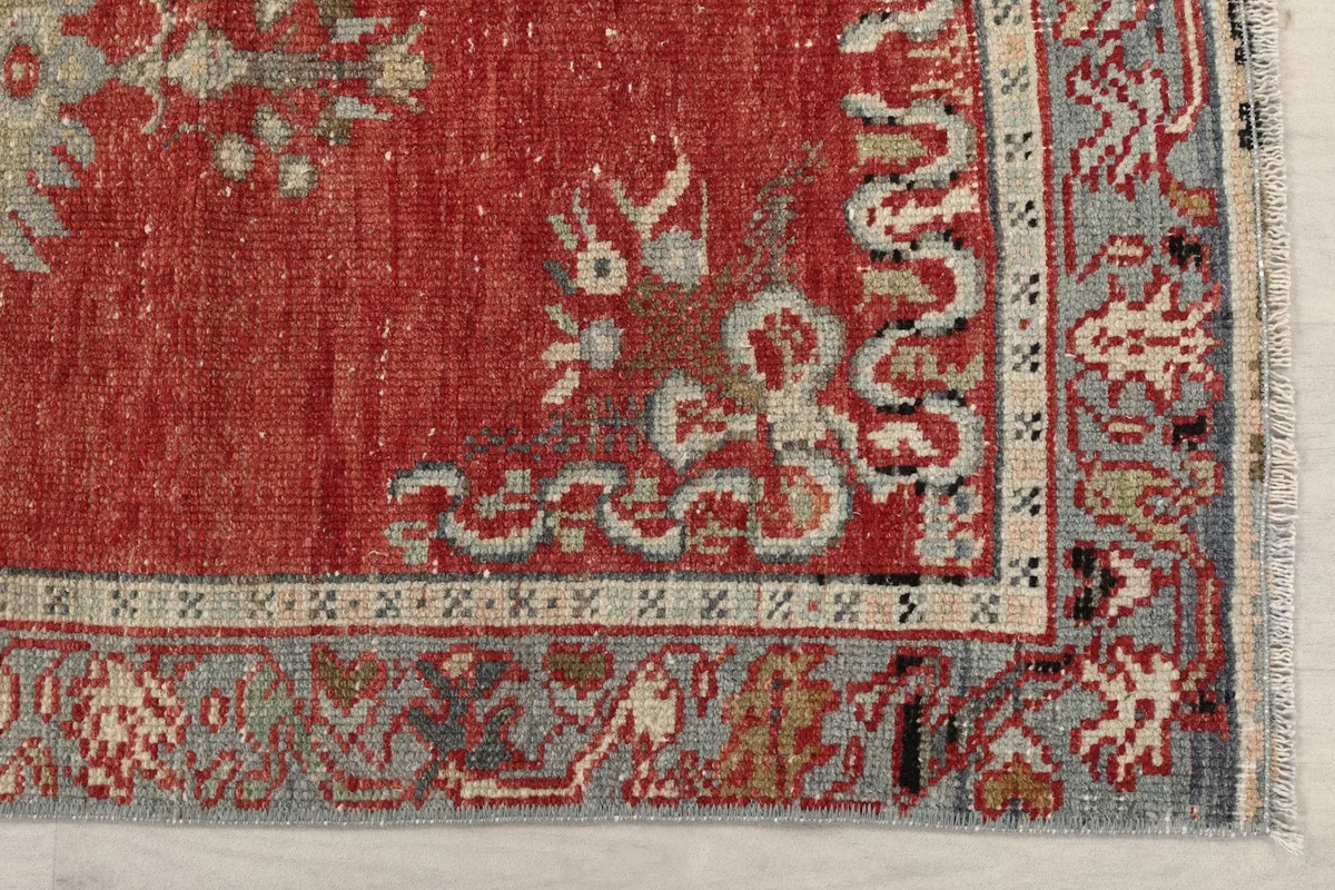 Detail of the gray-blue border and a corner of the red field, showing geometric patterns and fringe