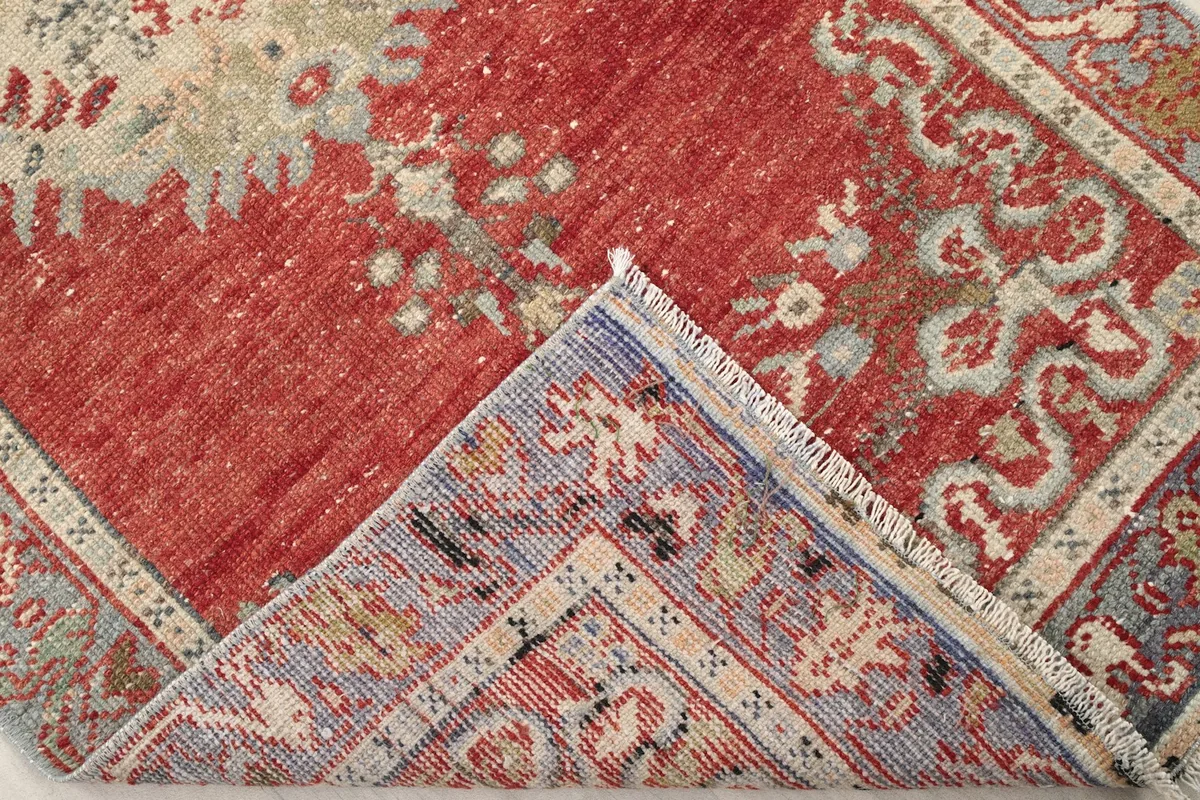 Folded corner of the rug revealing the cotton foundation and the reverse side of the hand-knotted wool