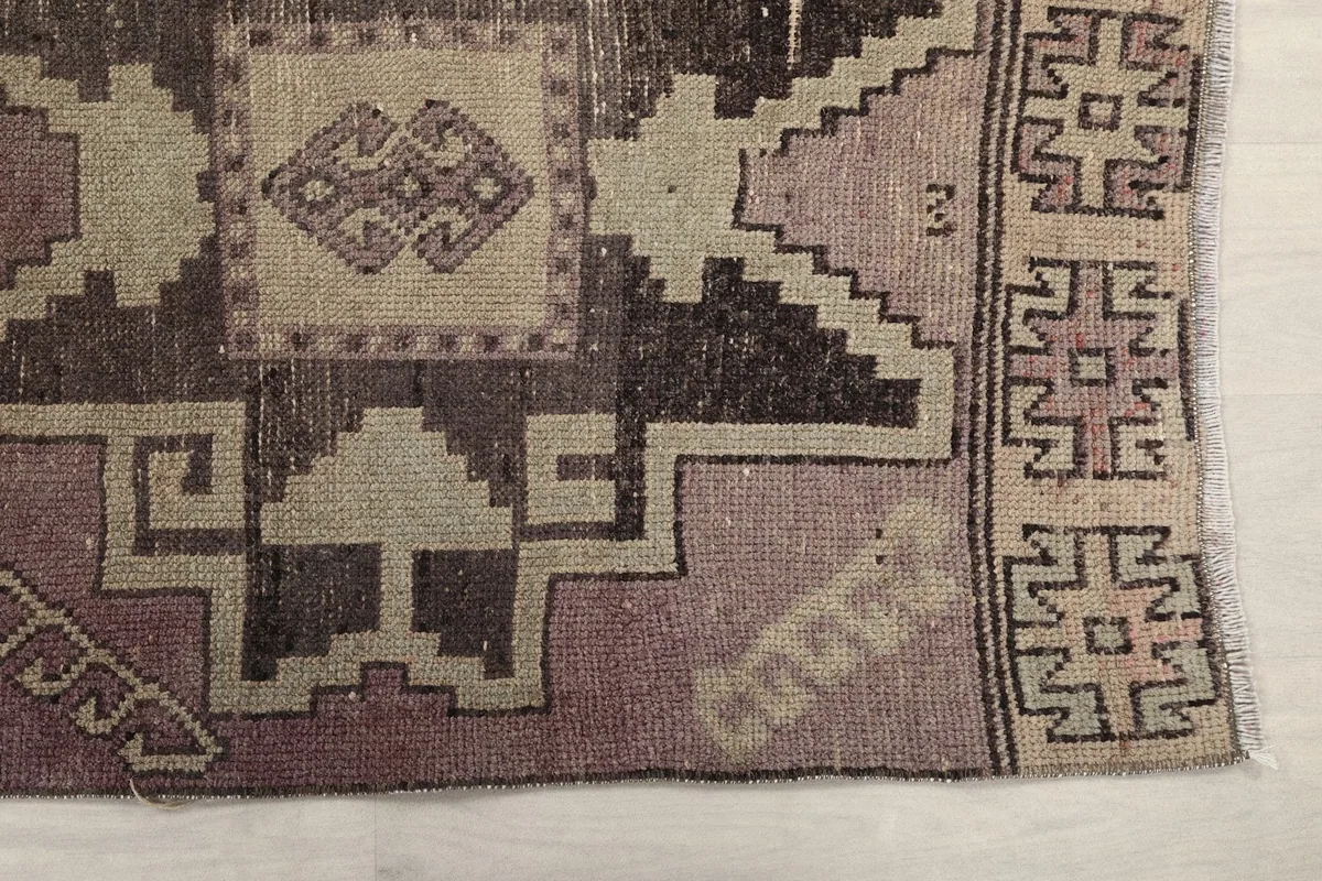 Detailed view of the runner's geometric motifs and color variations at one end, showing the charcoal and rose tones.