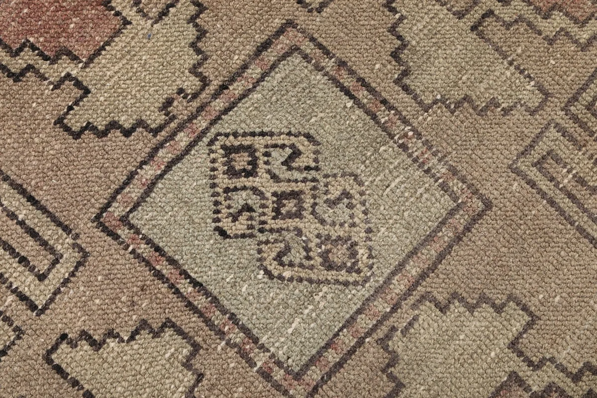 Macro detail of a specific tribal motif within a beige diamond shape, showing the hand-knotted wool texture.