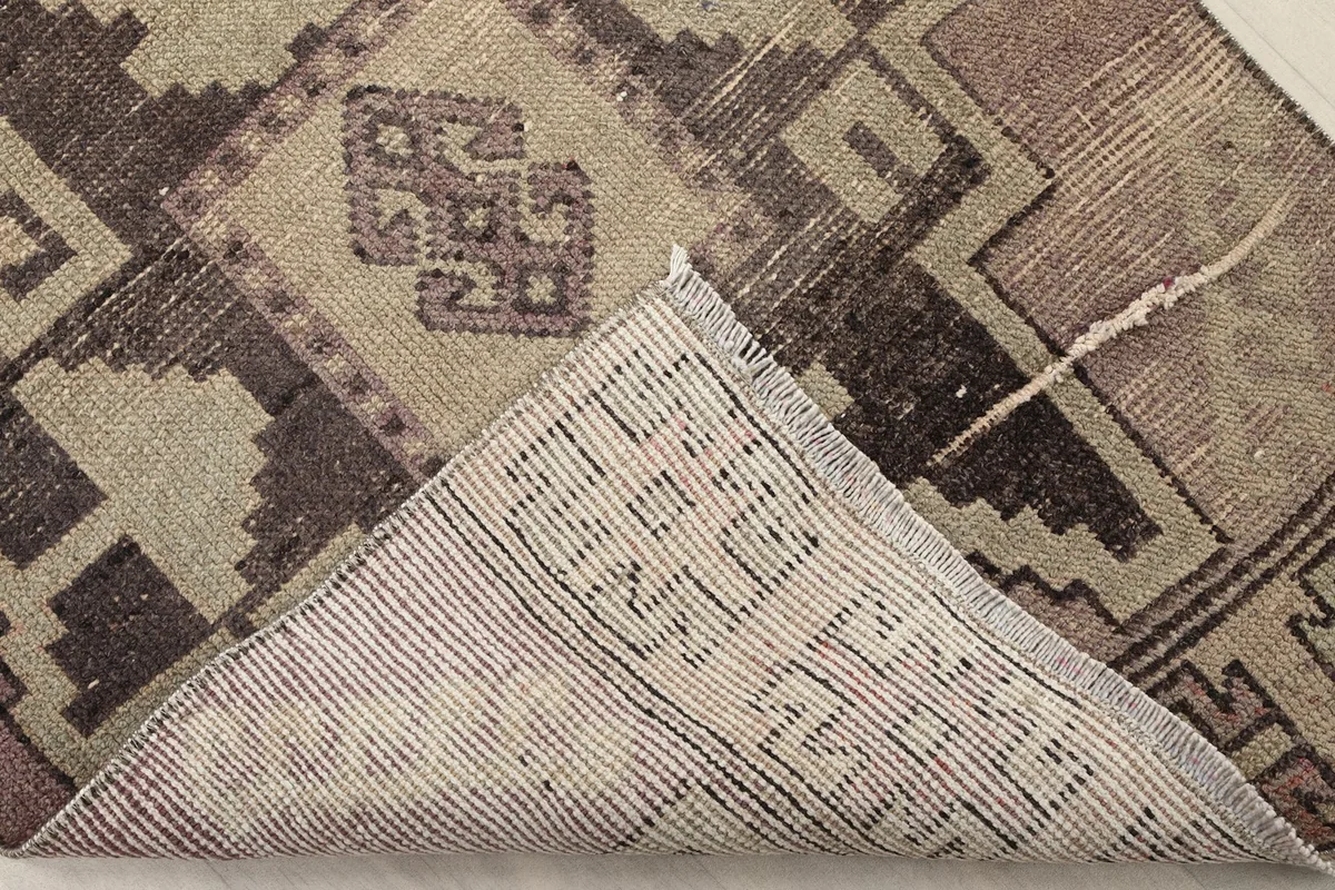 Underside view of a folded corner of the runner, revealing the cotton foundation and knotting structure.