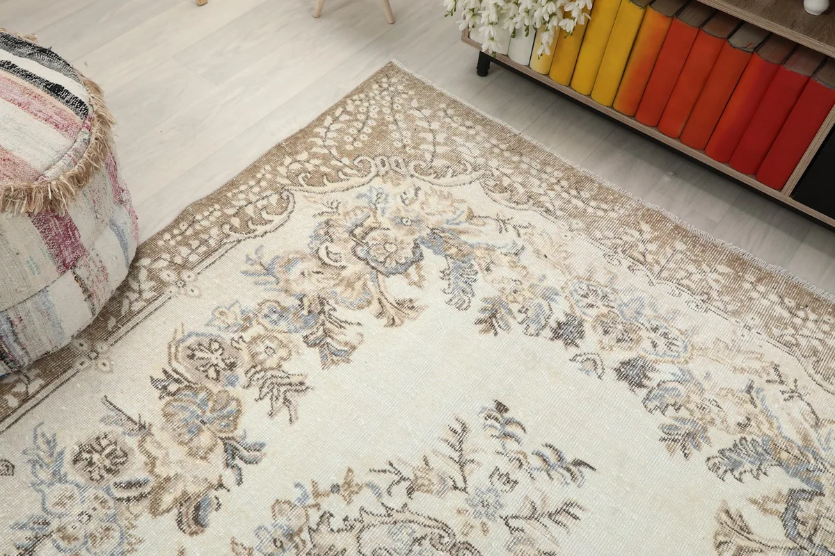Corner view of the rug, emphasizing the blend of cream and tan colors in the border design