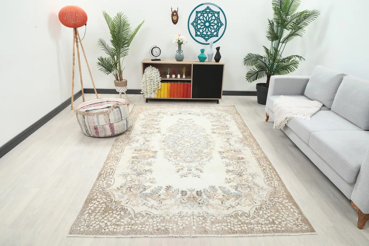 Vintage cream and tan rug displayed in a bright living room setting with a gray sofa
