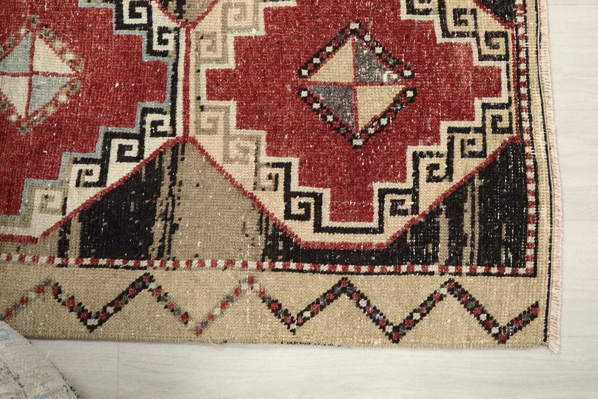 Detailed view of the lower right corner of the rug, showing a red medallion and beige border