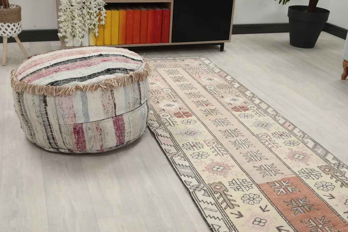 Close-up view of the runner rug in a room, next to a striped ottoman