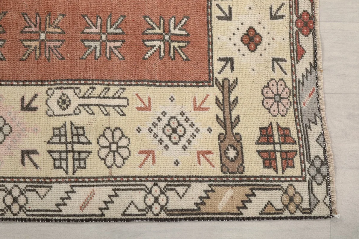 Detailed view of the rug's corner, showing cream field, rust accents, and geometric motifs