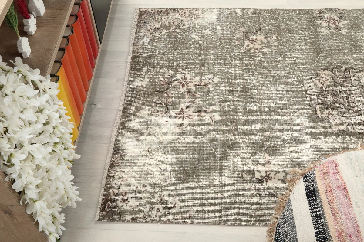 Angled shot of the rug's surface, capturing the subtle variations in color and wear across its design.