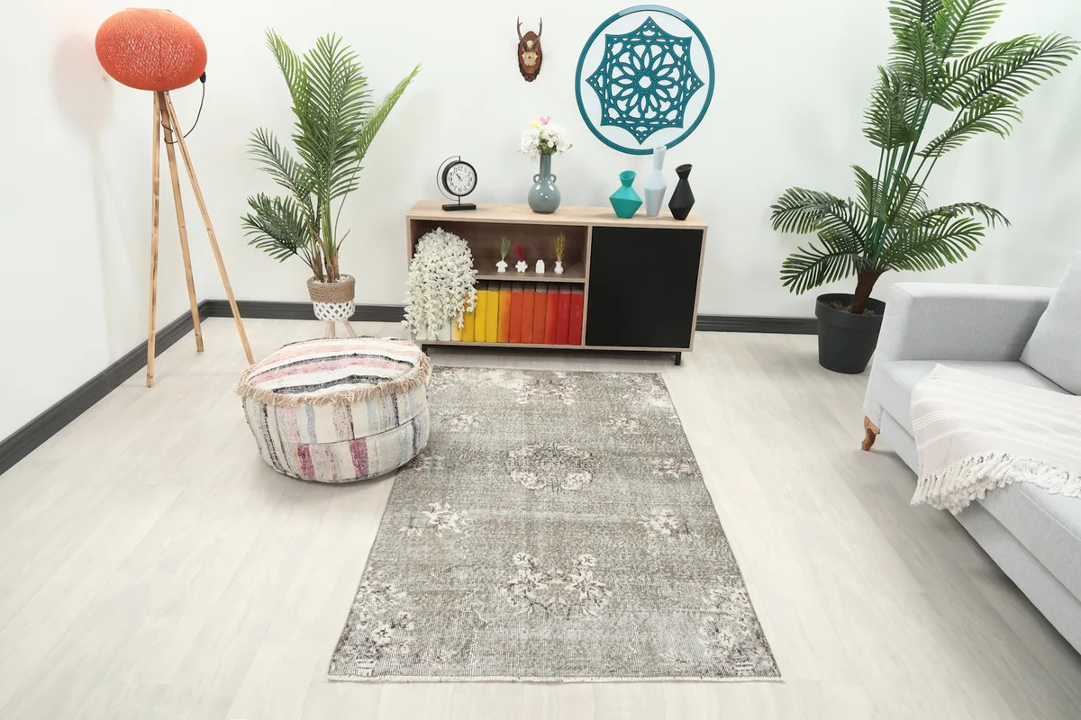 Vintage gray floral rug placed in a living room setting with light flooring and modern furniture.