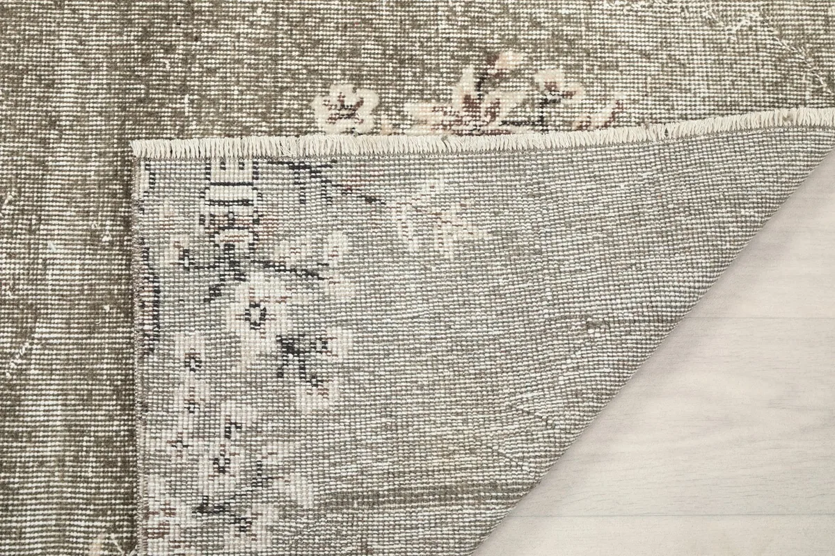 Close-up of the rug's underside, showing the reverse of the hand-knotted construction and fringe.