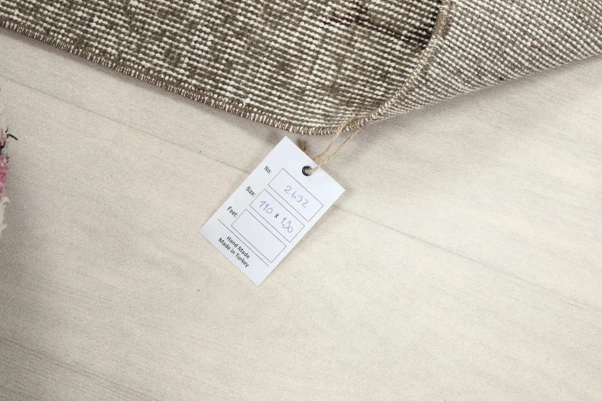 Product tag displaying the rug's size (110 x 190 cm) and origin (Hand-knotted in Turkey).