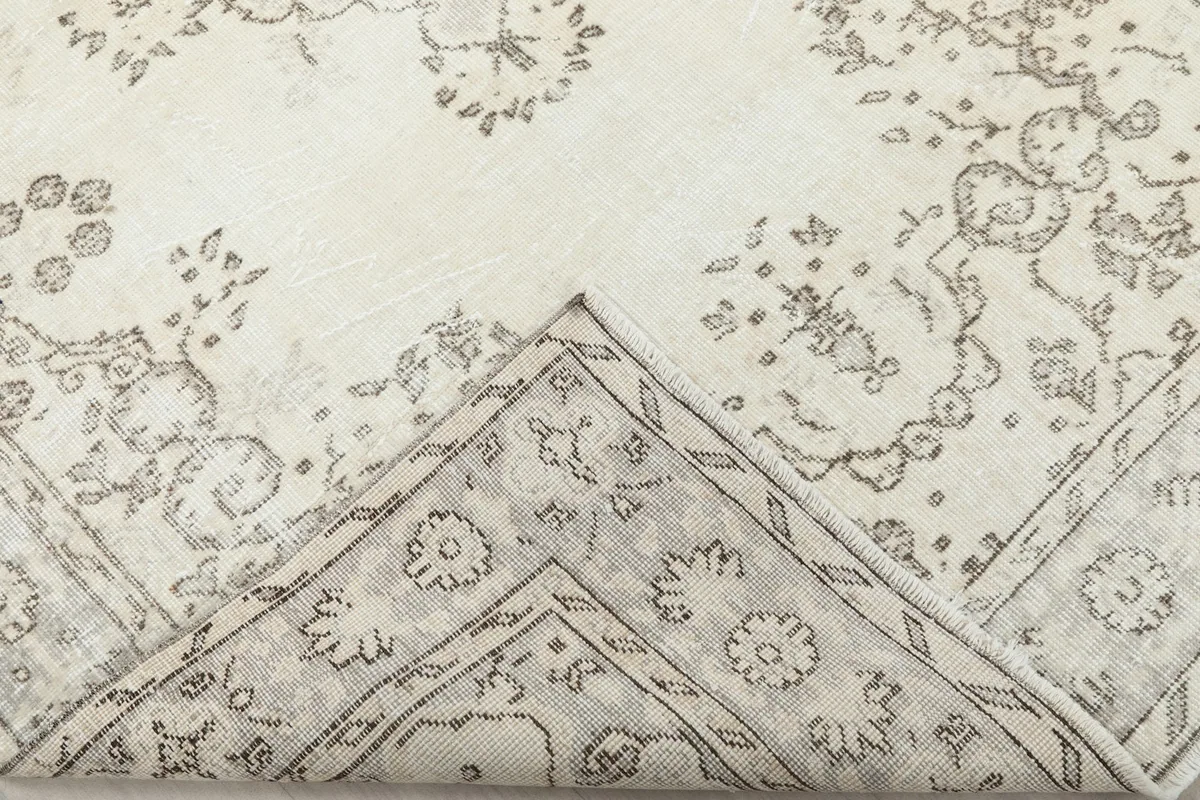View of the rug folded back to show the cotton foundation and the reverse side of the hand-knotted wool.