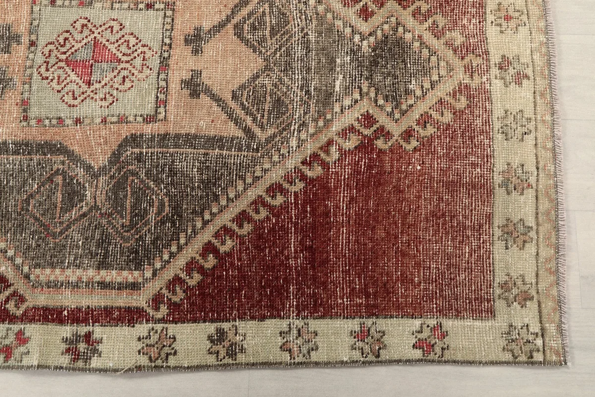 Detail of the rust field and beige border with small floral motifs on the runner.