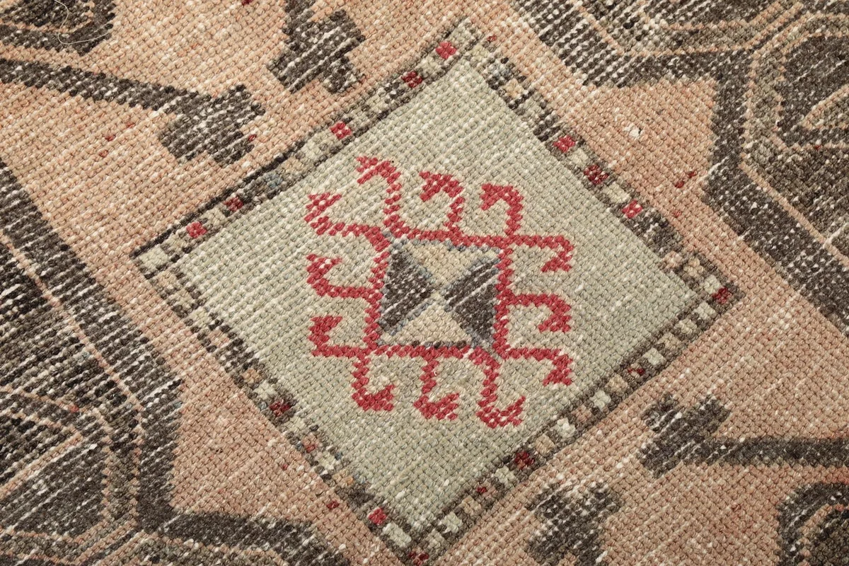 Extreme close-up of a tribal motif within a central medallion, showing wool texture.
