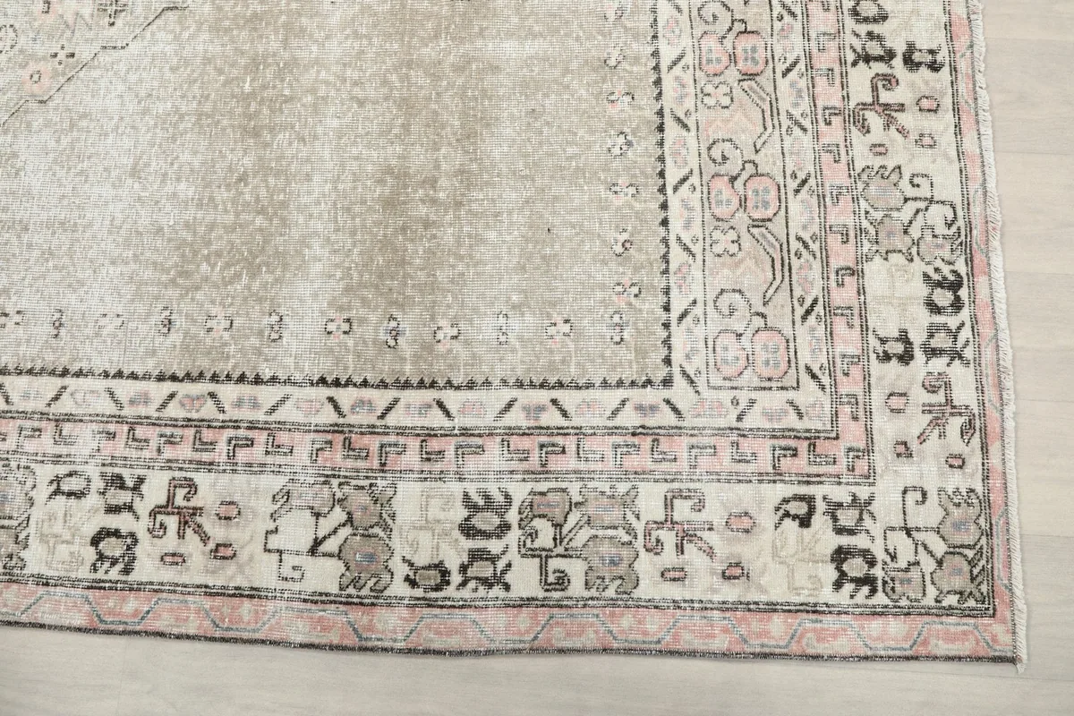 Close-up of the rug's intricate border with pink, black, and gray geometric motifs.