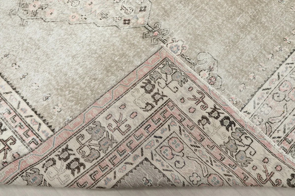 Folded corner of the rug, revealing the back of the hand-knotted wool on cotton foundation.
