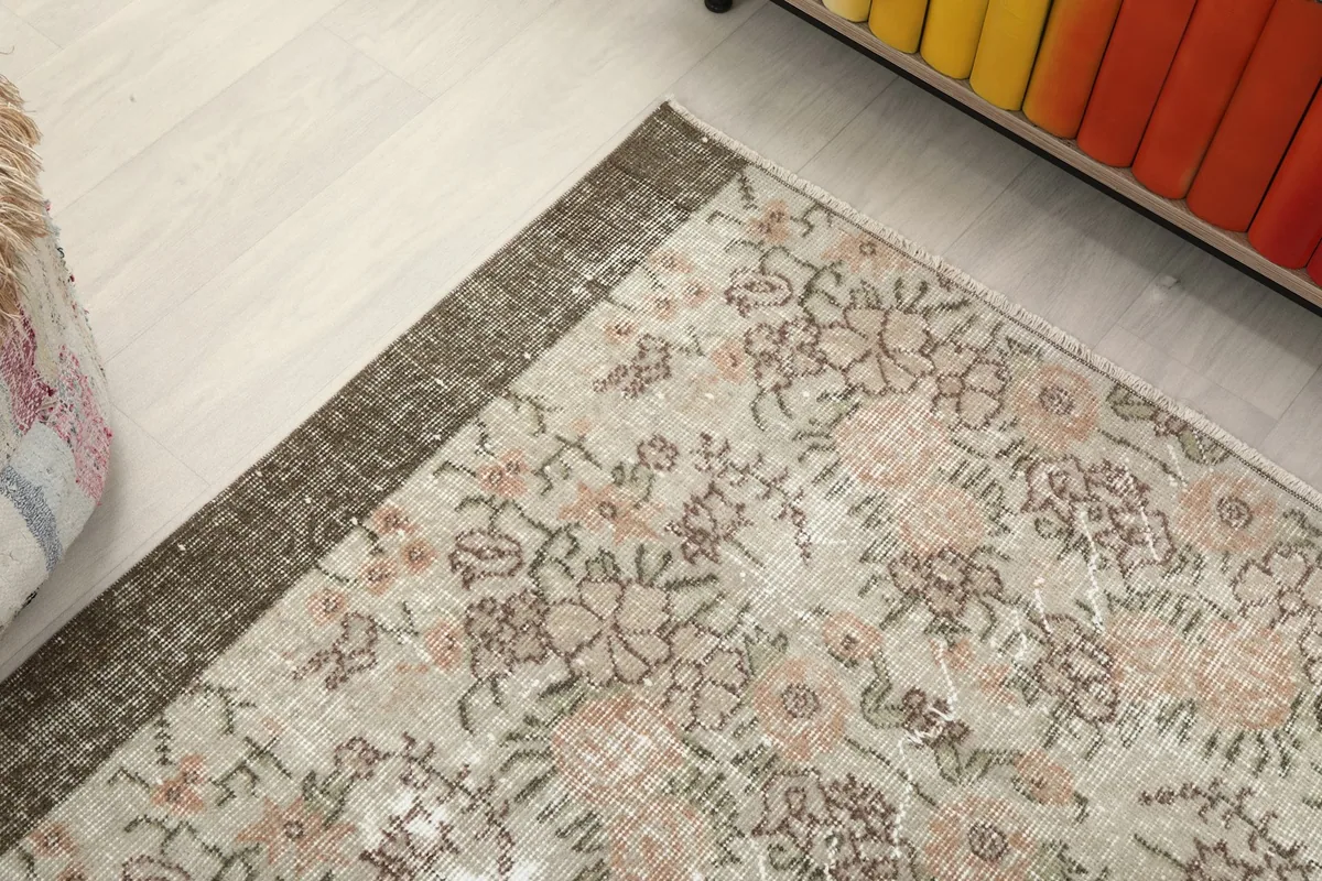 Corner view of the beige and rose rug, highlighting the distinct brown border