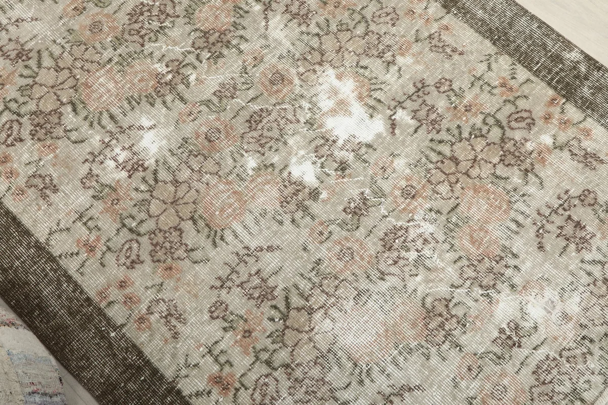 Overhead detail of the floral motifs and natural wear on the beige and rose rug