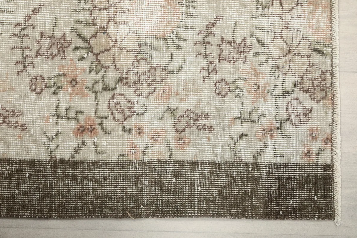 Detail view of the brown border and the transition to the beige floral field of the rug