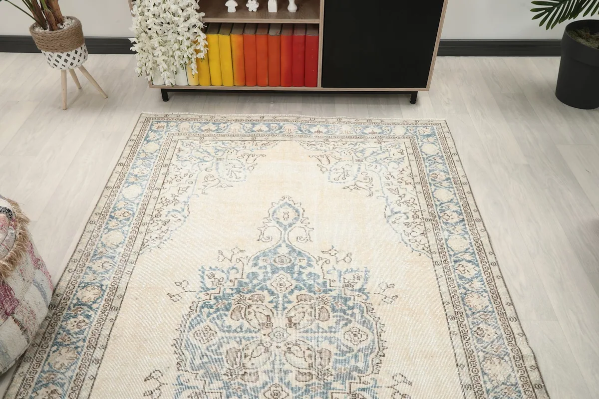 View of the vintage ivory and blue rug from one end in a room setting.