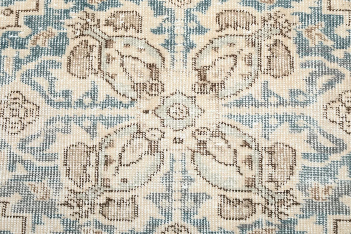 Close-up detail of the hand-knotted wool pile, showing blue and tan colors in the medallion.