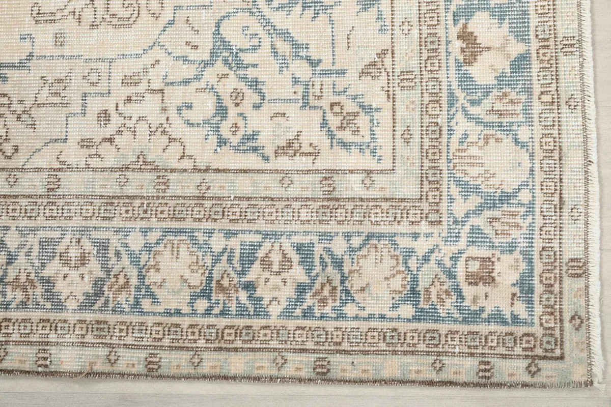 Detailed view of the blue and tan floral border design on the vintage Anatolian rug.
