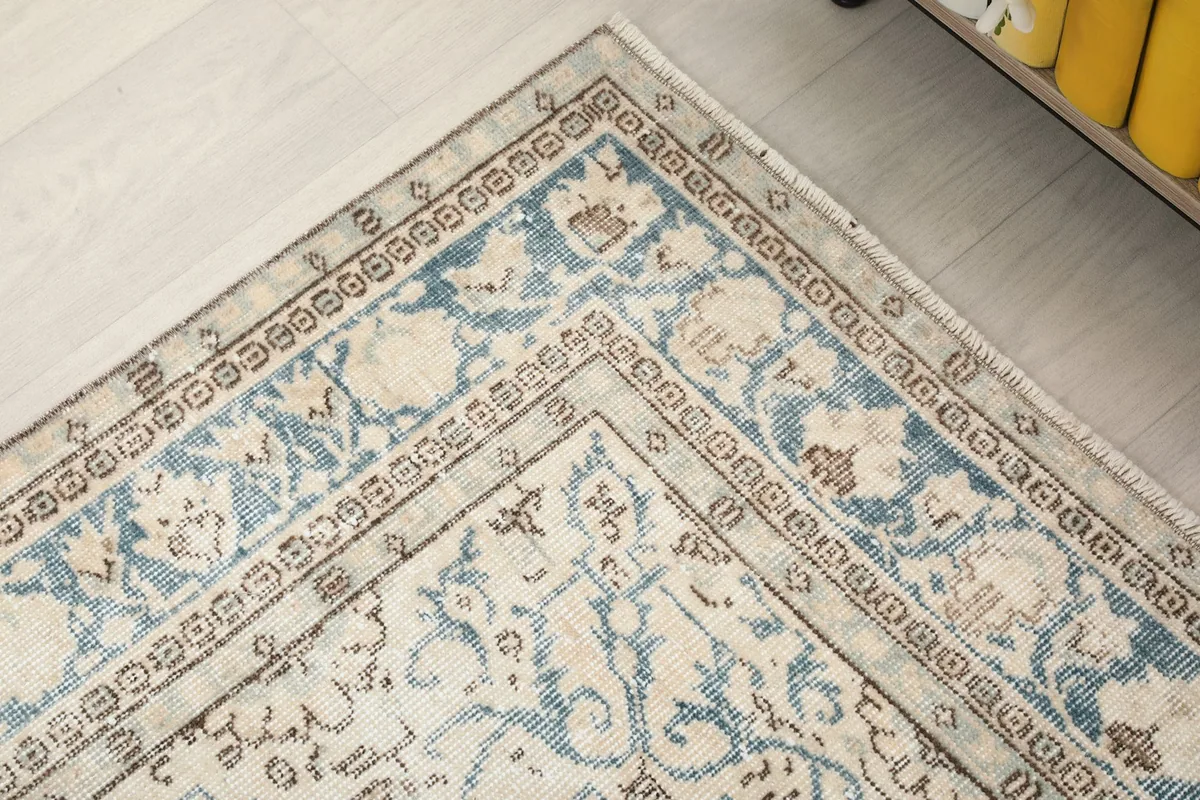 Corner detail of the rug's border, showcasing the intricate blue and tan patterns.