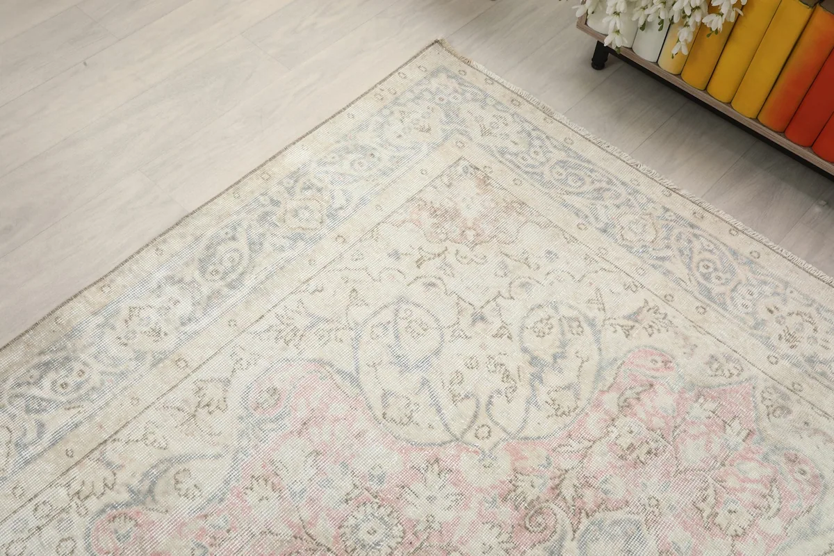 Diagonal view of the rug's corner and part of the field, showing the blend of cream, blue, and rose