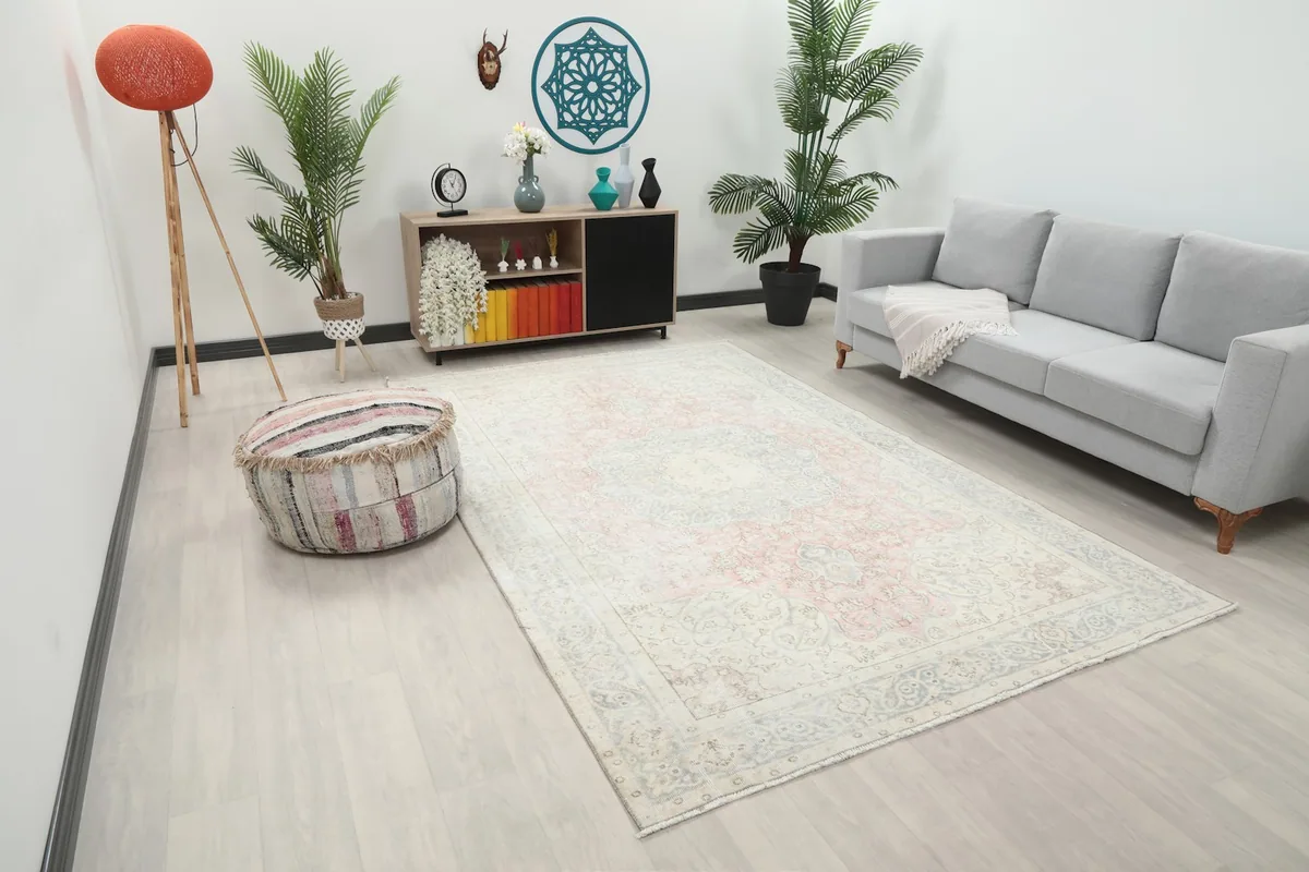 Angle view of the cream, blue, and rose medallion rug in a modern living room with light flooring