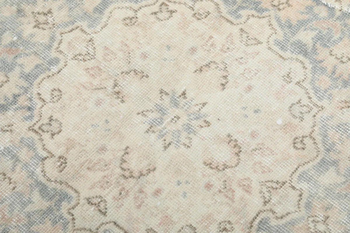 Detailed shot of the central motif within the medallion, showing cream and light blue hues