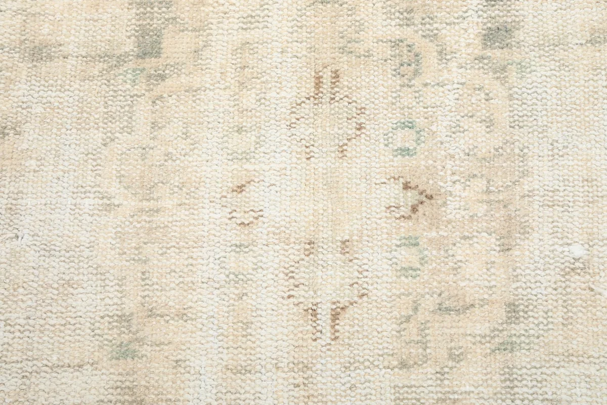 Close-up of the faded geometric motifs and low pile texture of the rug